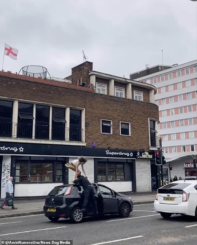 The driver jumps out of his car and thumps her in the ankle to get her off his vehicle