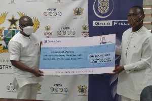 A Gold Fields official presents a cheque to Finance Minister Ofori Atta (left)