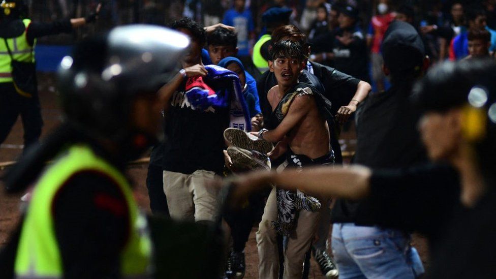 A group of people carry a man after a football match