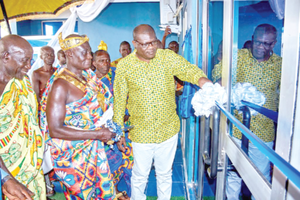 George Osei-Ameyaw (right), Board Chairman, Mponua Rural Bank, being supported by Nana Opoku Agyeman II, Chief of Amuana Praso, to cut tape to inuagurate the bank’s new headoffice building