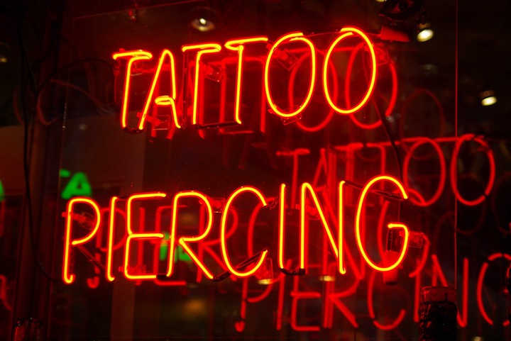 A neon sign reads "Tattoo Piercing"