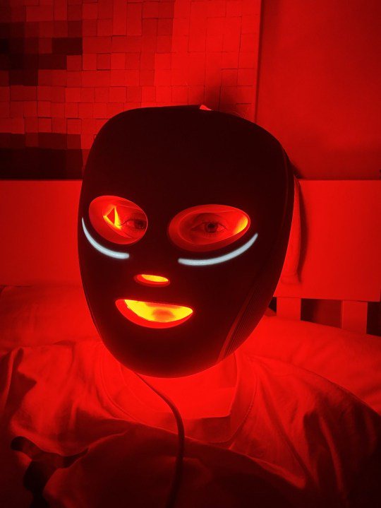 Image of Metro's Sarah Bradbury wearing the Shark CryoGlow Under-Eye Cooling & LED Anti-Ageing & Blemish Repair Mask, glowing red