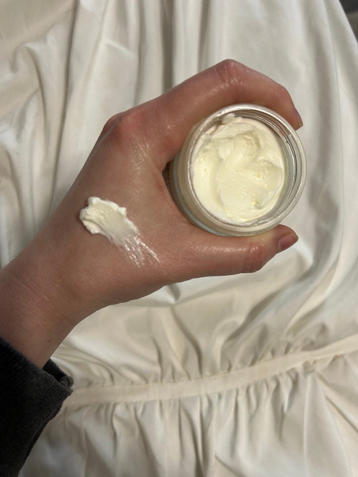 hand holding a jar of cream with a small amount applied on the wrist