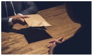 Photo of an individual offering money in a brown envelope attempting to influence the other